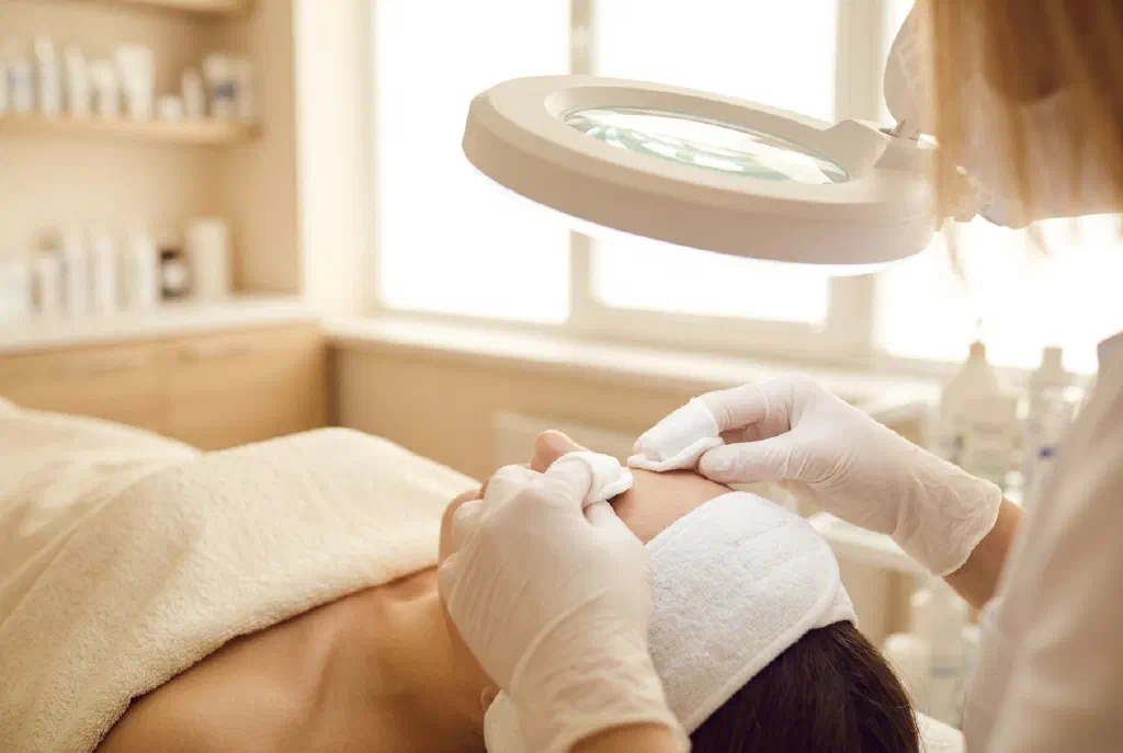 Chuyên viên thẩm mỹ làm sạch lỗ chân lông cho khách hàng trong một liệu trình chăm sóc da mặt