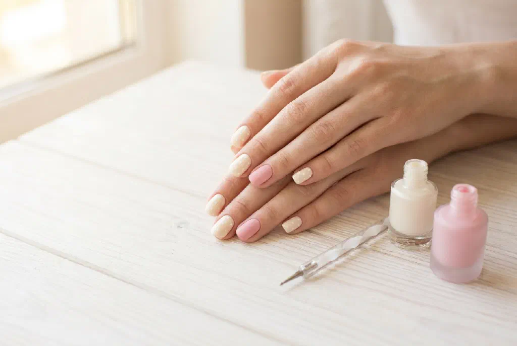 Hands with a simple nail design made of dots and colored accent nails