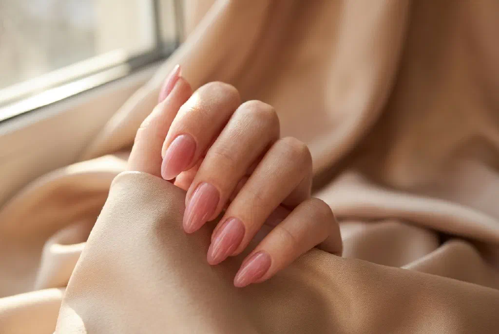 Gepflegte Polygel-Nägel in zartem Rosa mit natürlichem Glanz und mandelförmiger Spitze