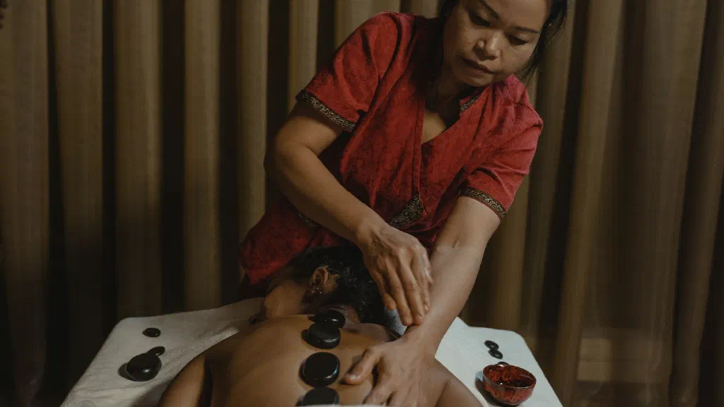 Đổ nước xông hơi bằng gáo gỗ lên đá sauna nóng